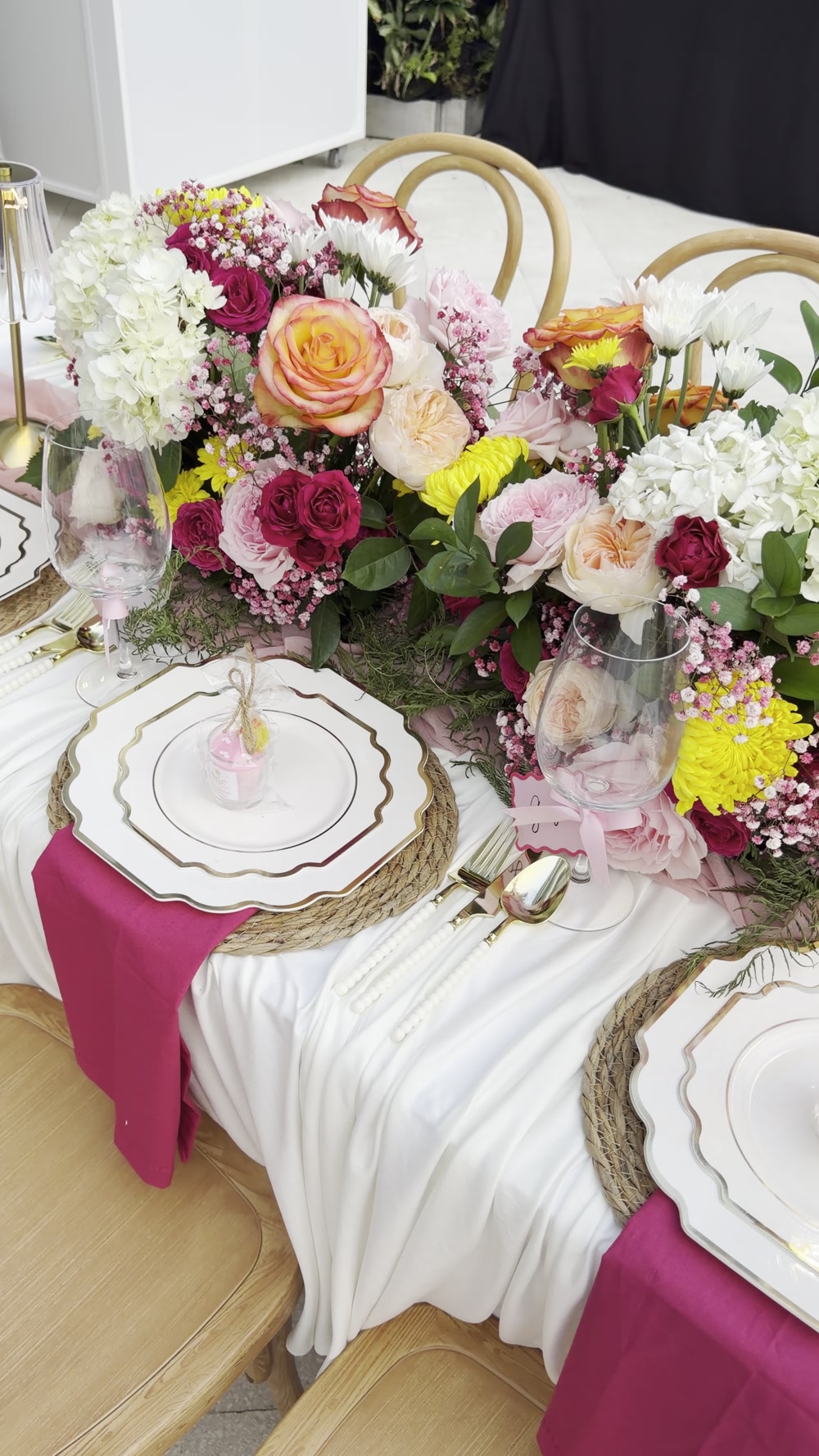 A lush baby-shower centerpiece with pink roses, white hydrangeas and yellow flowers