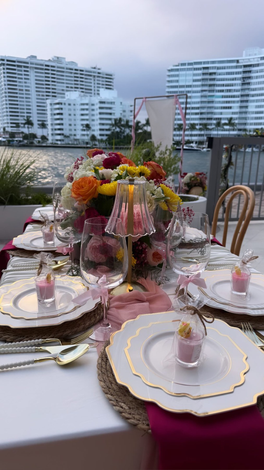 Baby-shower table with colorful flowers, pink ribbons and gold-edged plates