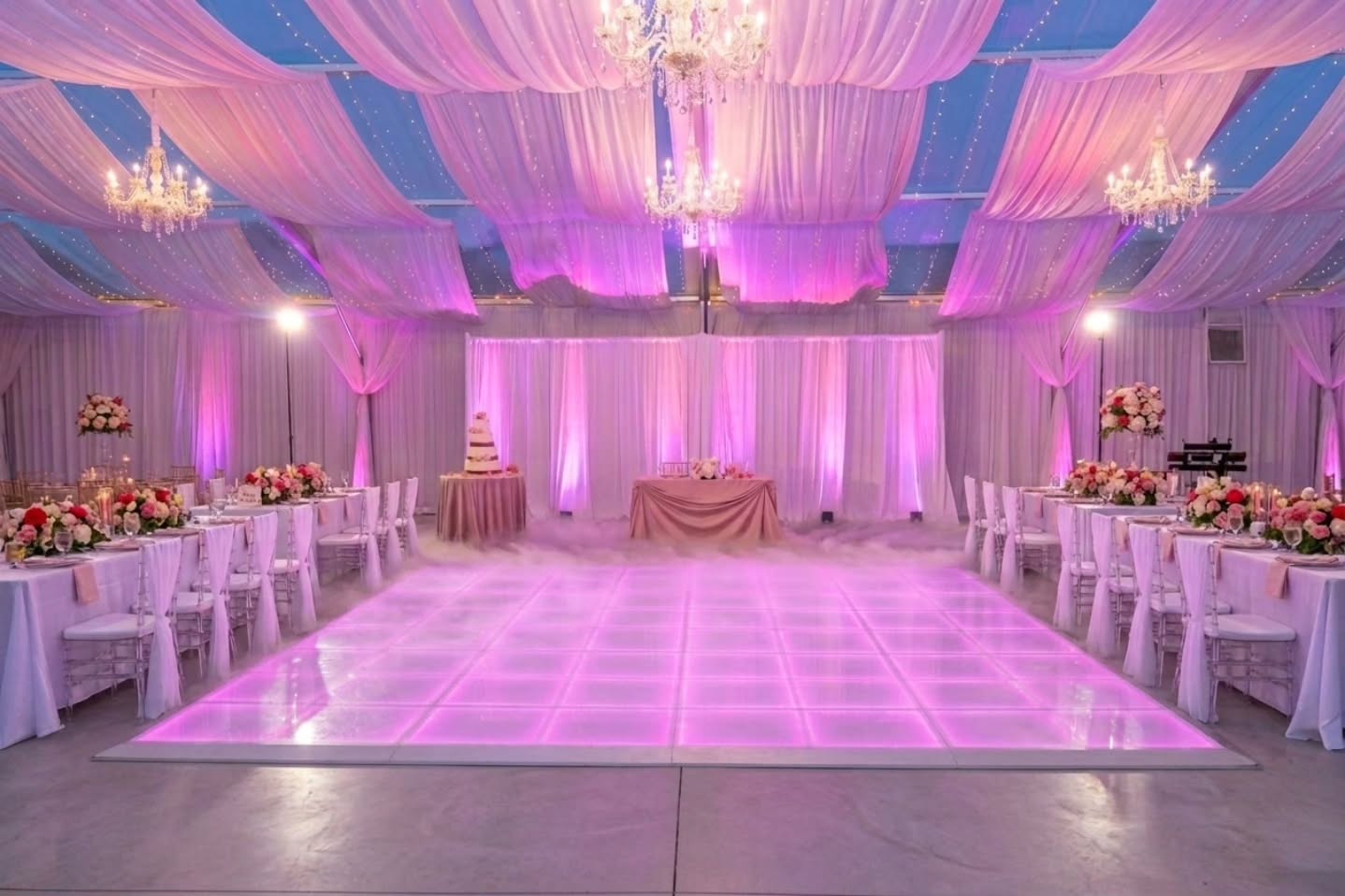 Ceiling draping, crystal chandeliers, and a pink-lit dance floor at a reception