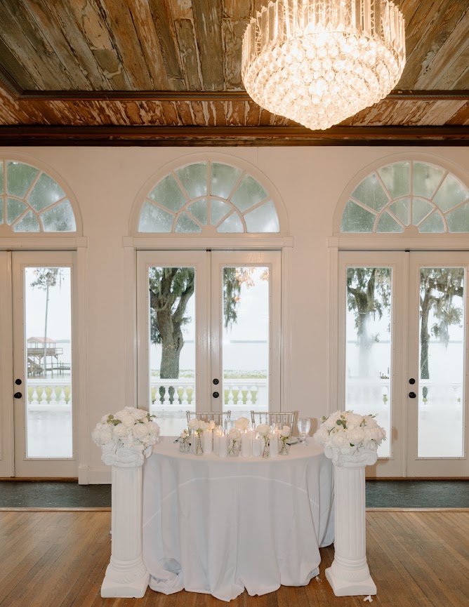 The couple’s white floral sweetheart table beneath a chandelier