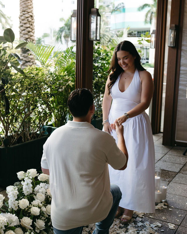 The bride-to-be smiling during the proposal among white roses and candles
