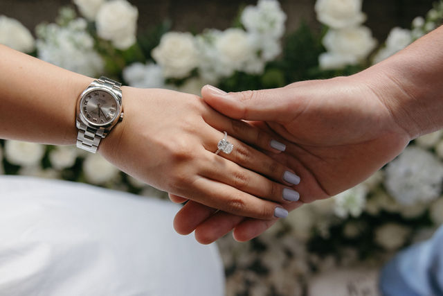The couple holding hands with the engagement ring