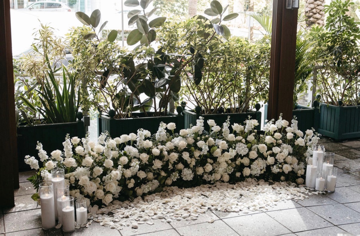 White flowers and pillar candles beside tall windows