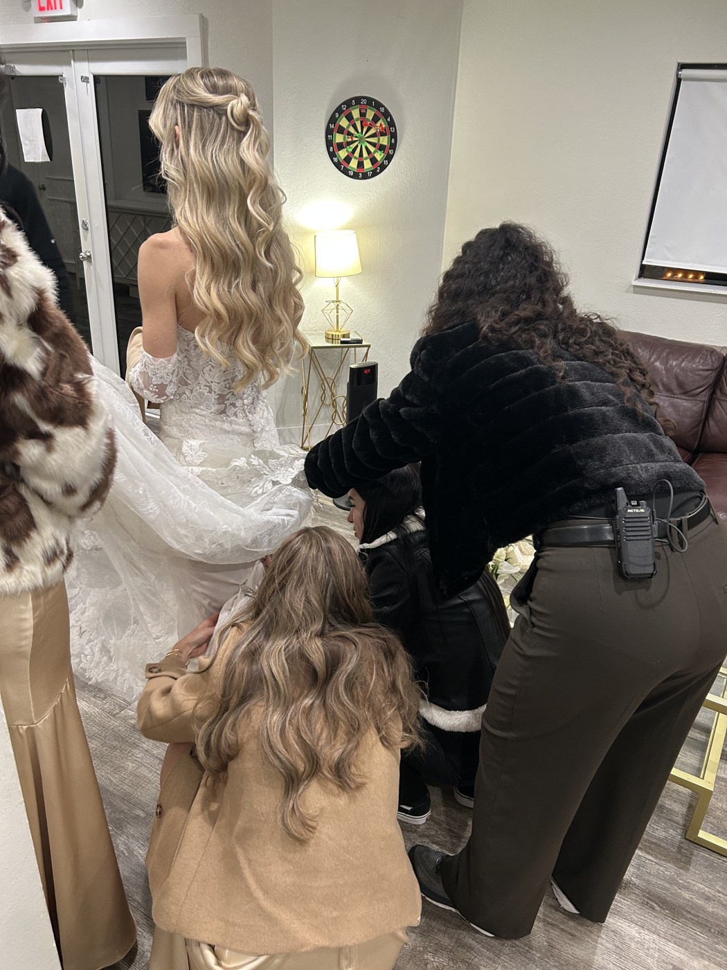 The team helping a bride with the finishing touches on her gown