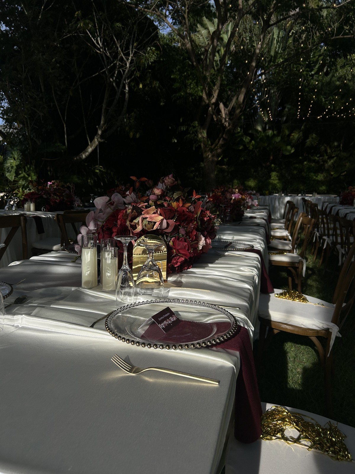 White linens, berry napkins, flowers, and candlelight at a garden reception