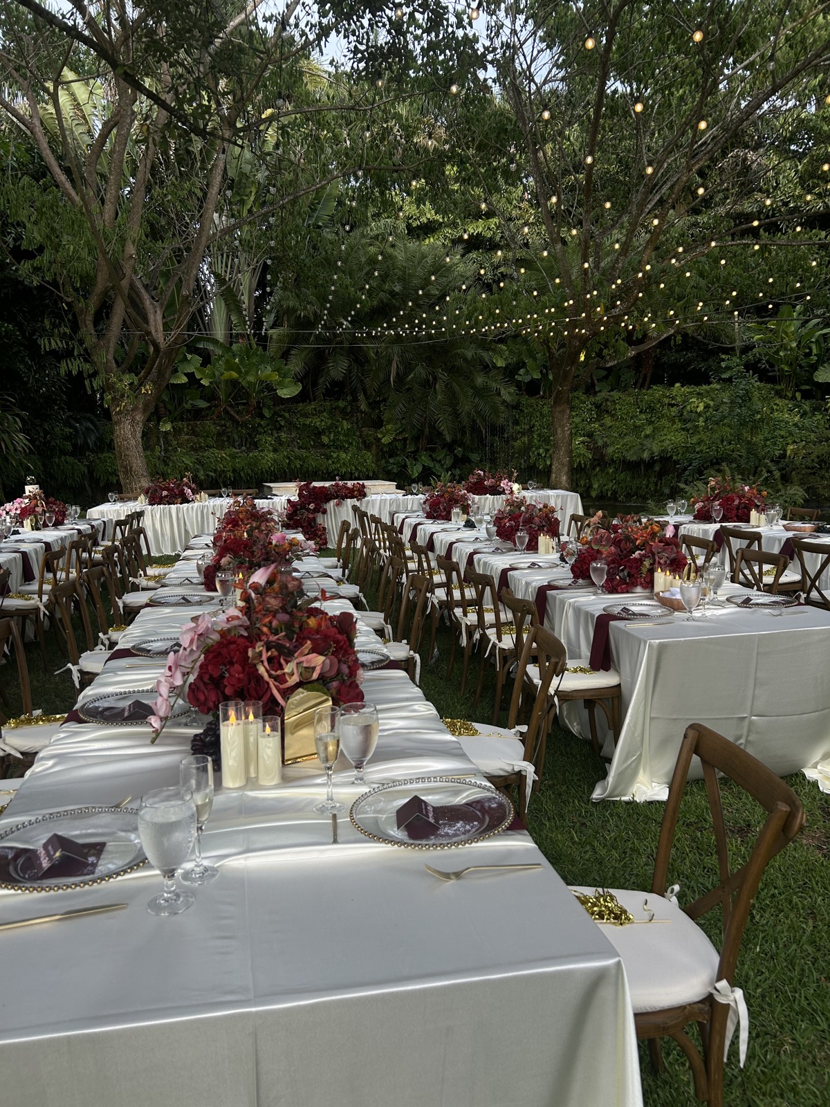 Garden reception tables with berry flowers beneath string lights